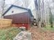 Home exterior featuring unique round window, wood siding and a glimpse of a wooden staircase in a lush environment at 110 N River Rd, Mcdonough, GA 30252