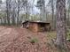 Small wooden cabin surrounded by towering trees in an overgrown natural environment at 110 N River Rd, Mcdonough, GA 30252