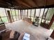 Sunroom with exposed ceiling beams, screened windows offering wooded views, and unfinished flooring at 110 N River Rd, Mcdonough, GA 30252
