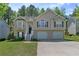 Classic two-story home featuring a two-car garage, mature lawn, and welcoming entrance staircase at 6983 Pine Shadow Way, Winston, GA 30187