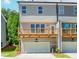 Exterior of the gray townhome featuring a garage and upper level wood balcony at 1250 Ainsworth Aly # 42, Sugar Hill, GA 30518
