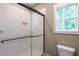 Bathroom with glass-enclosed shower, white tile, and a window for natural light at 939 Jean Ct, Covington, GA 30014