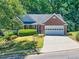 Charming brick home featuring a well-manicured lawn, mature trees, and a two-car garage at 1590 Highland Farm Dr, Suwanee, GA 30024