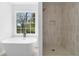 Bright bathroom featuring a modern tub with a window view and an elegant tiled walk-in shower at 3407 Deerwood Ct, Rex, GA 30273