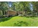 Brick home featuring a lush green lawn and a partially wooded lot providing both privacy and natural beauty at 4590 Lake Forrest Nw Dr, Atlanta, GA 30342
