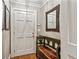 A welcoming entryway features a solid wood door and a quaint bench with a rustic mirror at 4590 Lake Forrest Nw Dr, Atlanta, GA 30342