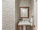 Stylish powder room features unique geometric wallpaper, a pedestal sink, and a classic mirror at 4590 Lake Forrest Nw Dr, Atlanta, GA 30342