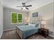 Cozy bedroom with a queen size bed, ceiling fan, bedside tables and view of lush green trees at 138 Grand Ave, Suwanee, GA 30024