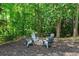 Inviting fire pit with Adirondack chairs set in a wooded backyard, providing a perfect spot for gatherings at 138 Grand Ave, Suwanee, GA 30024