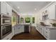 Well-lit kitchen with white cabinetry, stainless steel appliances, and a view of the dining area and backyard at 138 Grand Ave, Suwanee, GA 30024