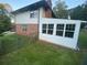 View of exterior featuring a brick house, sunroom with large windows, and spacious lawn at 753 Brookwood Sw Ter, Lilburn, GA 30047