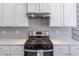 Modern kitchen with white cabinets, herringbone backsplash, and stainless steel appliances at 2797 Malton Way, Loganville, GA 30052