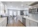 Modern kitchen and living space featuring white cabinets, stainless appliances, and an adjacent dining area at 2797 Malton Way, Loganville, GA 30052