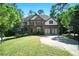 Beautiful two-story home featuring lush green lawn, mature trees and a basketball court on driveway at 3990 Old Spring House Ct, Atlanta, GA 30338