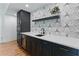 Close-up view of a stylish wet bar with marble counters, black cabinetry, and designer backsplash at 3990 Old Spring House Ct, Atlanta, GA 30338