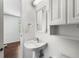 Bright bathroom featuring a pedestal sink, wall cabinet, and a glimpse into an adjacent room at 8827 Applegate Ln, Atlanta, GA 30350