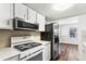 Well-lit kitchen featuring modern stainless steel appliances, white cabinetry, and adjacent dining area at 8827 Applegate Ln, Atlanta, GA 30350