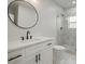Bathroom features a round mirror, vanity with black hardware, toilet, and glass-enclosed shower at 1441 Ezra Church Nw Dr, Atlanta, GA 30314
