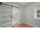 Modern bedroom featuring wood floors, white walls, and a sliding barn door leading to the bathroom at 1441 Ezra Church Nw Dr, Atlanta, GA 30314
