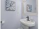 Stylish powder room showcasing a pedestal sink with decorative mirror and flower artwork at 1803 Gold Finch Way, Lawrenceville, GA 30043
