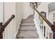 A carpeted staircase features dark wood railings and white balusters leading to the upper levels of the home at 1803 Gold Finch Way, Lawrenceville, GA 30043