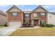 Classic brick home featuring an attached two-car garage, manicured landscaping, and a cozy front entrance at 2620 Paddock Point Pl, Dacula, GA 30019