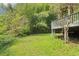 Grassy backyard beneath an elevated deck surrounded by lush greenery and trees at 454 Jo Ann Se Dr, Marietta, GA 30067