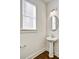 Stylish powder room featuring a pedestal sink, round mirror, and a window providing natural light at 2240 Mulsanne Dr, Lithonia, GA 30058