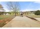 Spacious backyard features large patio with a grill and lush green lawn, framed by mature trees and a blue sky at 552 Trotters Ln, Mcdonough, GA 30252