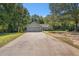 Wide driveway leading to a grey home surrounded by lush trees and a green lawn at 5623 Yeager Dr, Douglasville, GA 30135