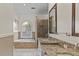 Bright bathroom with a soaking tub under an arched window and granite counters at 168 Jersey Rd, Oxford, GA 30054