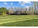 Large grassy lawn leading up to a brick home surrounded by many tall, mature trees at 168 Jersey Rd, Oxford, GA 30054