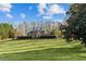 Expansive lawn leads to a stately brick home with mature trees, complemented by blue skies at 168 Jersey Rd, Oxford, GA 30054