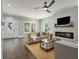 Bright living room with hardwood floors, a ceiling fan, and a cozy fireplace with a TV above at 490 Third Ave, Scottdale, GA 30079