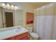 Bathroom featuring a single sink vanity, toilet, shower with curtain, and wood storage cabinet at 1005 Berkeley Woods Dr, Duluth, GA 30096