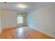 A bright, empty bedroom with gleaming hardwood floors and a sunlit window at 1005 Berkeley Woods Dr, Duluth, GA 30096