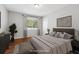 This staged bedroom has a large window, wood floors, and a neutral color palette at 681 Counsel Dr, Marietta, GA 30068