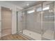 Large tiled shower with glass doors, a built-in niche, and plenty of natural light at 616 Leafy Branch Way, Mcdonough, GA 30253