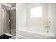 Bright bathroom featuring tile shower, large soaking tub, and window for natural light at 7586 Jennadee Dr, Fairburn, GA 30213