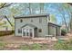 Backyard with a patio, a table, green exterior with multiple windows, trees, and foliage at 835 Ridge Ave, Stone Mountain, GA 30083
