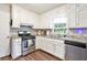 Corner view of kitchen featuring white cabinets, stainless appliances and dark wood-look floors at 835 Ridge Ave, Stone Mountain, GA 30083