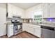 Bright kitchen featuring white cabinets, granite counters, stainless steel appliances and wood-look floors at 835 Ridge Ave, Stone Mountain, GA 30083