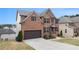 Brick home featuring a spacious driveway and dark shutters, complemented by lush green landscaping at 4604 Marching Ln, Fairburn, GA 30213