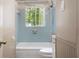 Bathroom with blue tiles surrounding a tub and shower, and a window providing natural light at 37 Crystal River Dr, Riverdale, GA 30274
