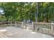 A wooden deck with black railings, offering a scenic view of a lush backyard and wooded area at 37 Crystal River Dr, Riverdale, GA 30274