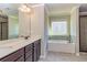 A luxurious bathroom features a double vanity, soaking tub, and tiled shower, bathed in natural light at 3835 Rifflepool Ct, Douglasville, GA 30135