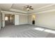 Spacious bedroom with a tray ceiling, fan, plush carpet, and a door leading to the en suite bath at 3835 Rifflepool Ct, Douglasville, GA 30135