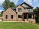 Beautiful brick two-story home with black trim windows, a covered porch, and lush green lawn at 6120 Hutchins Dr, Buford, GA 30518