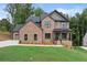 Charming two-story brick home with a well-manicured lawn and modern black framed windows at 6120 Hutchins Dr, Buford, GA 30518