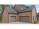 Attached two car garage doors with decorative details and coach lights in brick facade at 6120 Hutchins Dr, Buford, GA 30518